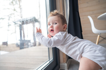 Baby boy standing by the patio window. 