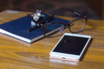 smart-phone Glasses book pen and watch on wood table for business or education concept