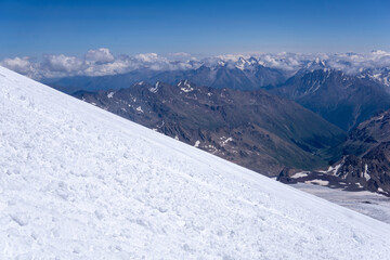 mountain landscape, view from highland icefield on slope to mountain ranges in the clouds, view from the Mount Elbrus to the Main Caucasian Range