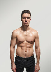 Portrait of a young, muscular man standing confidently without a shirt. He exudes strength, fitness, and determination, ideal for health and fitness themes.