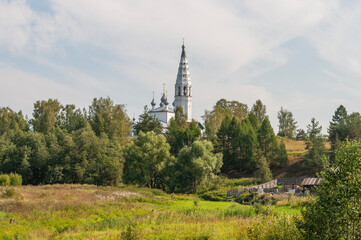 Summer country landscape, domes of the old church in the distance. Cathedral of the Transfiguration of the Savior in Sudislavl, Kostroma region, Russia