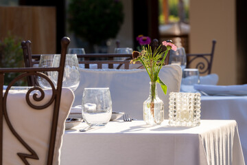 White tablecloth dinner in the sunshine, with flowers.