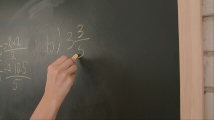 Close up of woman hand writing math sample and formula on chalkboard, professor writes on blackboard or student solving task. Education and science concept.