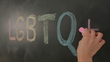 Close up of woman hand writing text letters lgbt with colorful chalks on chalkboard, Diversity and...