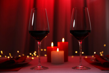 Burning candles and wine in glasses on table against blurred lights