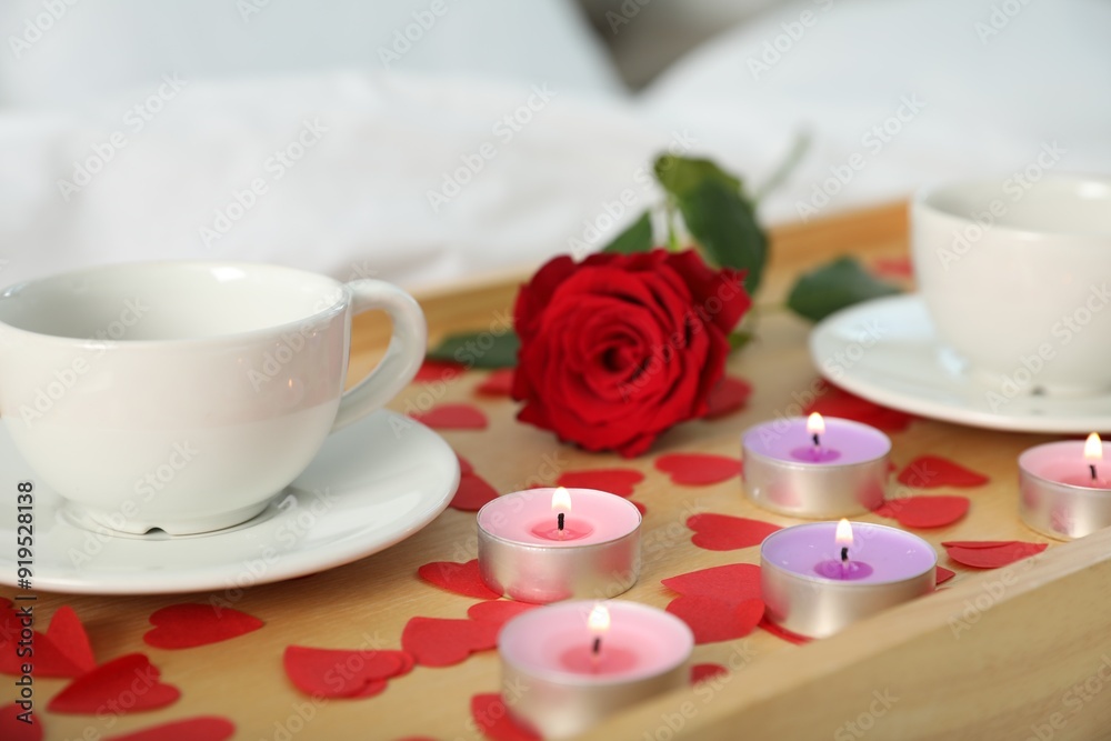 Canvas Prints Wooden tray with burning candles, rose, cups of drink and red paper hearts on bed indoors, closeup