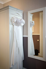 White wedding dress with stones in the room on a hanger.