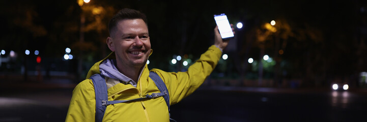 Man in yellow coat holding mobile phone in hand