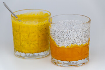 Chia pudding with coconut milk and mango puree in a glass on a white background.