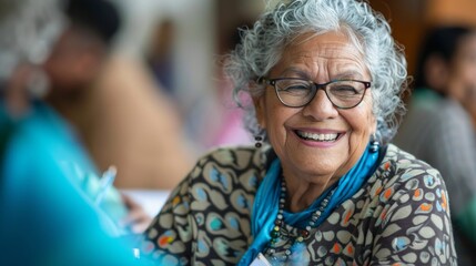 Elderly woman in a joyful moment, smiling at a dining table surrounded by vague silhouettes. Social gathering atmosphere with genuine happiness.
