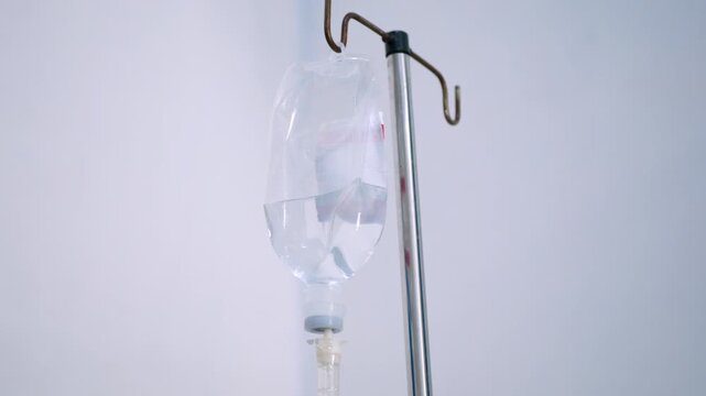 close up view of saline IV drip bag and Infusion pump hanging on stainless pole in the patient room at the hospital