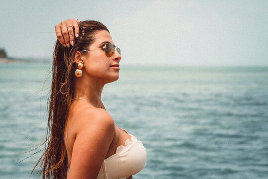 Beautiful face woman bikini model wearing aviator sunglasses and golden jewelry at the beach in northeast brazil