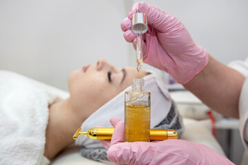 Fototapeta premium closeup of beauticians hands is putting few drops essential oil with a pipette on the face women