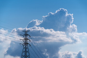 A high voltage tower and a sea of raging, tumbling clouds on a summer morning. View of the mountains surrounding Emerald Reservoir. Xindian District, Taiwan.