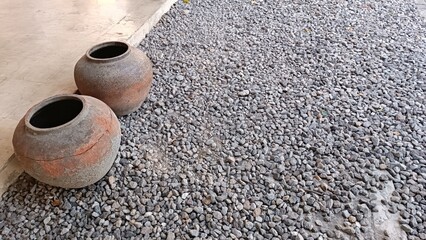 Two old vases are sitting on a gravel ground