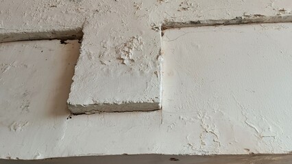 A white wall with a rough texture and a few cracks