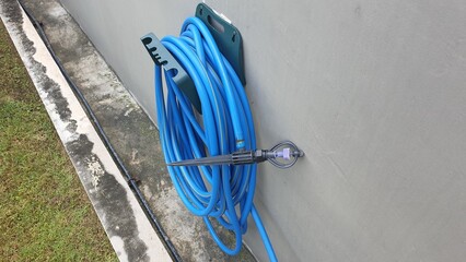 A set of the rubber watering hose and water springer hung on the wall.