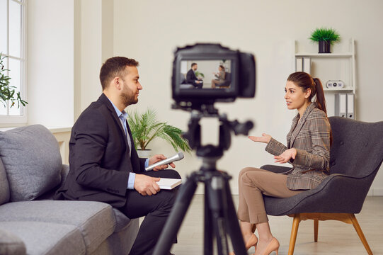 Man is conducting an interview with a woman, recording it with a video camera or broadcasting live. Tv interview, news show, talk show or pr event. Reporter engaged in conversation with woman.