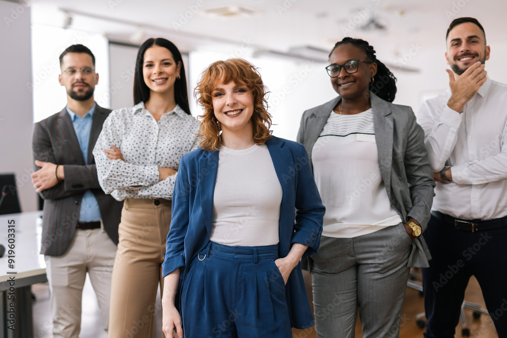 Wall mural portrait of young ceo businesswoman standing with her hands crossed in front of her colleagues.