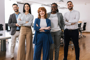 Portrait of young CEO businesswoman standing  with her hands crossed in front of her colleagues.