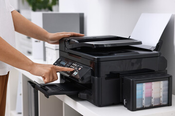 Woman using modern printer at workplace indoors, closeup