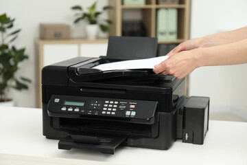 Woman using modern printer at workplace indoors, closeup