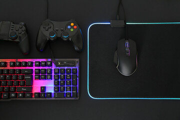 Computer mouse, RGB keyboard and game controllers on black background, flat lay © New Africa