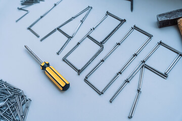 The word work is laid out from nails of different sizes on a gray background with hand tools.