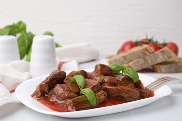 Tasty stew with okra, tomato sauce, bread and basil on white tiled table, closeup