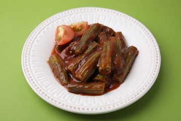Tasty stew with okra and tomato sauce on light green background, closeup