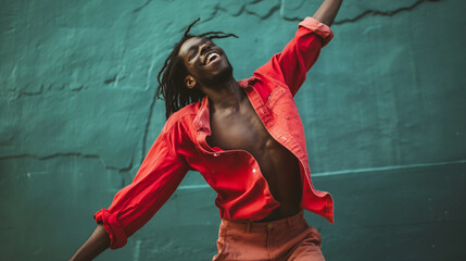 Photograph capturing the energy and movement of an individual in a radiant red shirt performing a dynamic dance against a contrasting green textured wall.