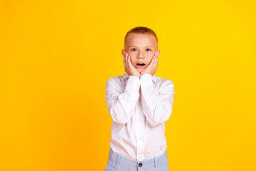 Photo of excited cute clever diligent boy wear white shirt uniform empty space isolated on yellow color background