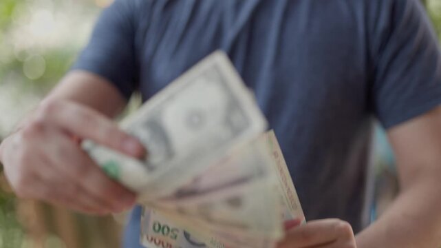 hands of a man holding US dollar and mexican pesos. Money exchange concept
