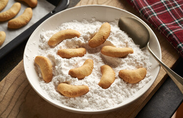 Coating homemade Christmas cookies called vanilla crescents or Kipferl in vanilla sugar