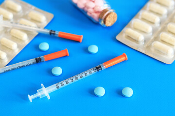 Insulin syringes and vitamins on a blue background. Diabetes treatment. Medicine and health...