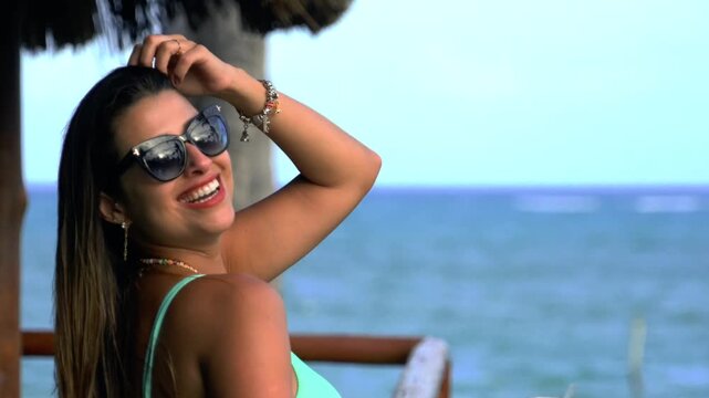 Beautiful face woman bikini model wearing sunglasses and golden jewelry at the beach in northeast brazil