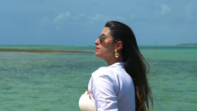 Beautiful face woman bikini model wearing sunglasses and golden jewelry at the beach in northeast brazil