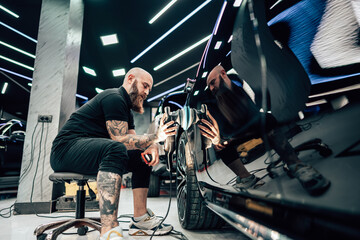 Professional vehicle polishing and detailing service in a modern car workshop. Brightly lit...