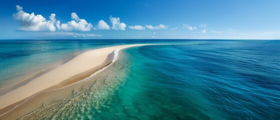Obraz premium A large body of water with a sandy shore in the foreground and a blue sky adorned with clouds in the background