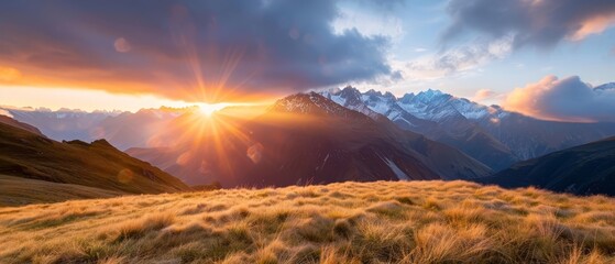  Sun sets over grassy field with tall foreground grass and mountain range background