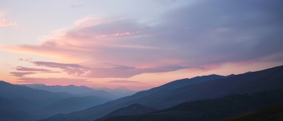 Fototapeta premium A mountain range backdrop with a pink-blue sky and clouds in the foreground