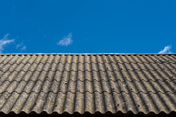 An old brick barn in the Polish countryside with a corrugated asbestos roof.