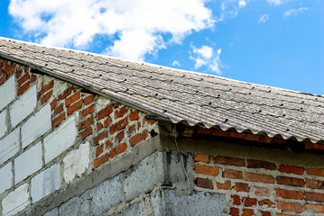 An old brick barn in the Polish countryside with a corrugated asbestos roof.