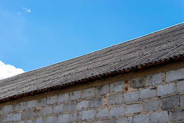 An old brick barn in the Polish countryside with a corrugated asbestos roof.