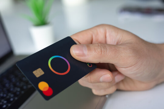 Man hand holding plastic card Payoneer Mastercard laptop Apple Macbook