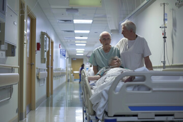 Obraz premium Elderly patient in a hospital bed receiving a visit from a healthcare worker in a clinical corridor.