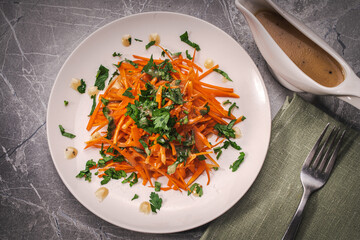 Carrot and parsley salad with Vinaigrette sauce on a white plate on a gray background. A place to copy the space.
