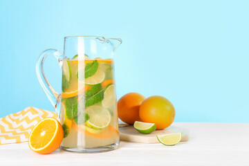 Freshly made lemonade with mint in jug on white wooden table against light blue background, space for text