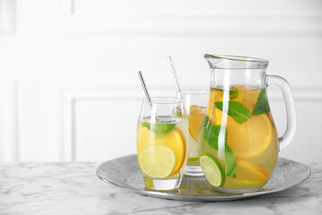 Freshly made lemonade with mint in jug and glasses on white marble table