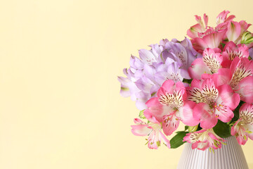 Beautiful alstroemeria flowers in vase on beige background, closeup. Space for text